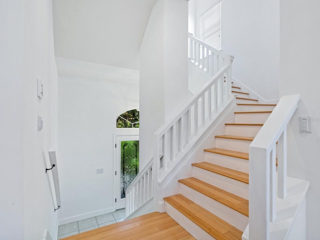 staircase with tile patterned flooring and a towering ceiling