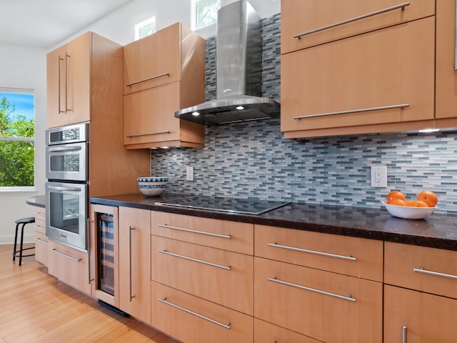 kitchen featuring beverage cooler, black electric stovetop, stainless steel double oven, wall chimney exhaust hood, and backsplash