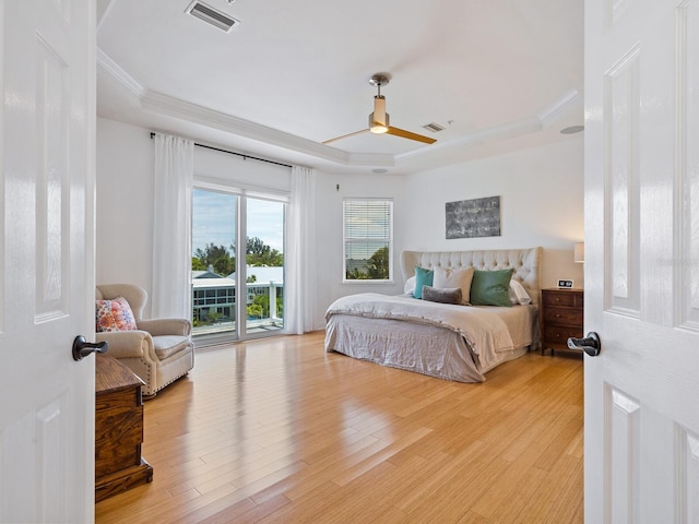 bedroom featuring wood-type flooring, a raised ceiling, ceiling fan, and access to outside