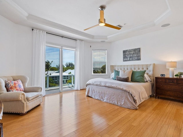 bedroom featuring access to exterior, ceiling fan, hardwood / wood-style flooring, a tray ceiling, and crown molding