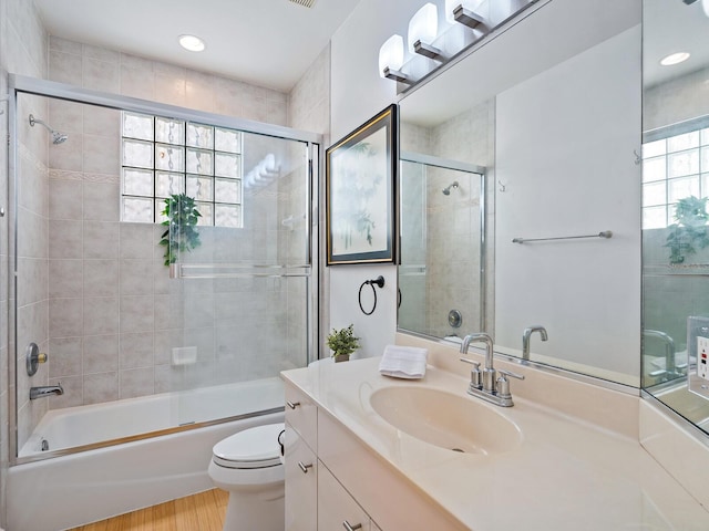 full bathroom with a healthy amount of sunlight, shower / bath combination with glass door, hardwood / wood-style flooring, and toilet