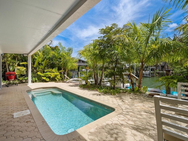 view of swimming pool featuring a patio area and a water view