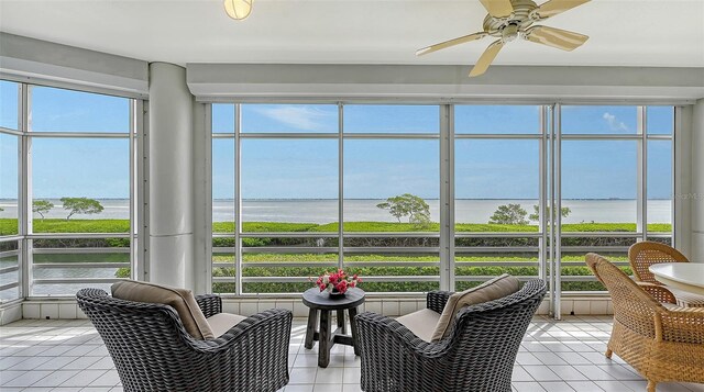 sunroom with ceiling fan and a water view