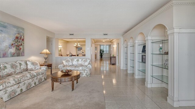 living room with tile flooring, ornamental molding, decorative columns, and an inviting chandelier