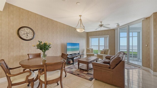 living room featuring ceiling fan, a water view, and light tile floors