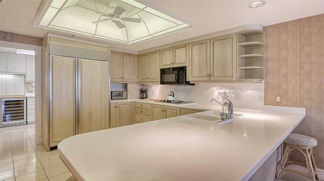 kitchen featuring a breakfast bar, kitchen peninsula, paneled built in fridge, sink, and ceiling fan