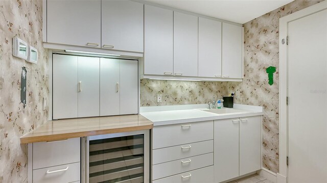 bar with white cabinets, sink, and beverage cooler