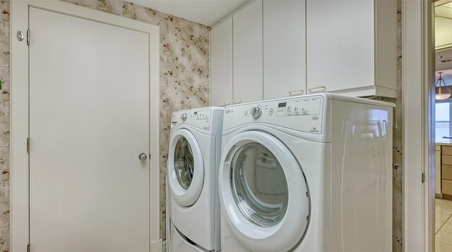 laundry area with independent washer and dryer, cabinets, and light tile floors