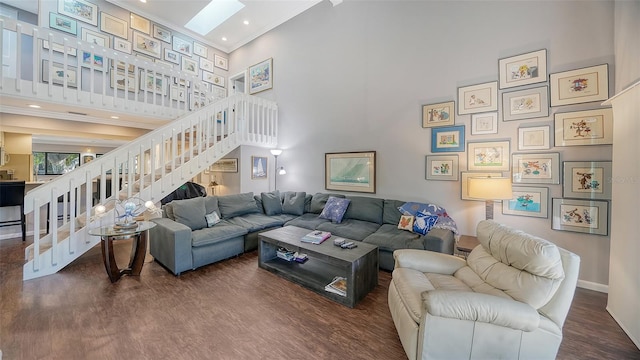 living room featuring a skylight, dark hardwood / wood-style flooring, and high vaulted ceiling