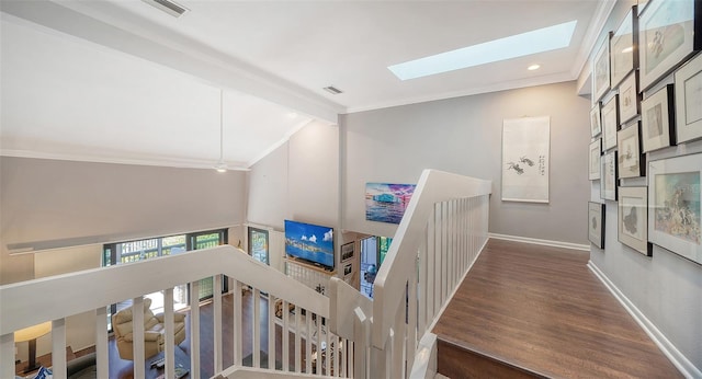 stairway with lofted ceiling with skylight, crown molding, and dark wood-type flooring