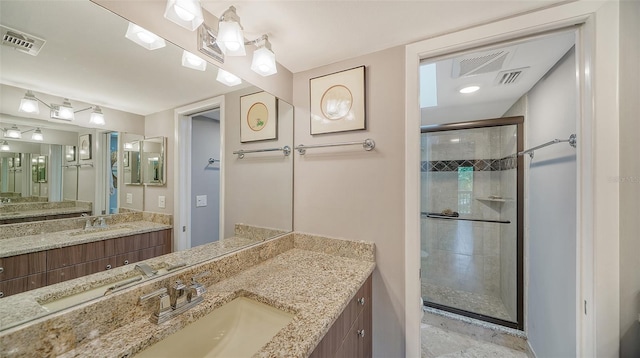 bathroom with a shower with shower door, vanity, and tile floors