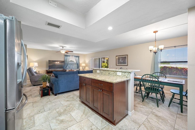 kitchen with a center island, hanging light fixtures, ceiling fan with notable chandelier, light stone counters, and stainless steel fridge with ice dispenser