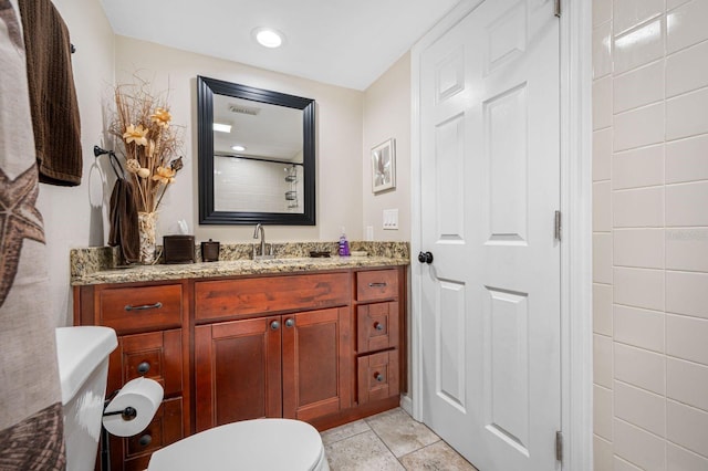 bathroom featuring tile flooring, vanity, and toilet