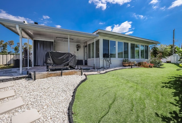 rear view of property with a patio, a sunroom, and a lawn