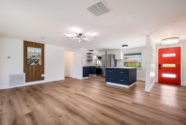 unfurnished living room featuring a chandelier and light wood-type flooring