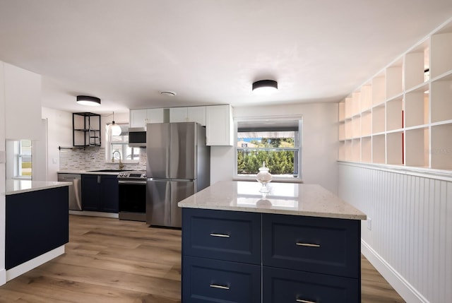 kitchen featuring light stone counters, white cabinets, light hardwood / wood-style floors, tasteful backsplash, and stainless steel appliances