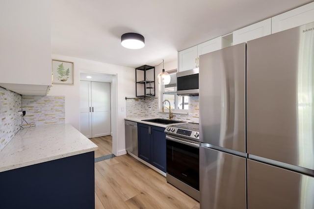 kitchen featuring white cabinets, sink, light hardwood / wood-style floors, backsplash, and stainless steel appliances