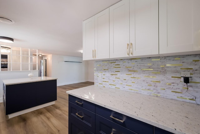 kitchen featuring tasteful backsplash, light hardwood / wood-style floors, white cabinetry, and light stone countertops