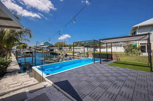 view of pool with a dock, a patio area, a lawn, and a water view