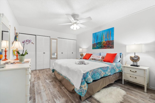 bedroom with multiple closets, ceiling fan, a textured ceiling, and light wood-type flooring