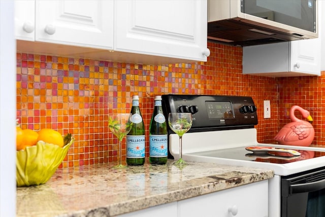 kitchen featuring backsplash, black / electric stove, and white cabinetry