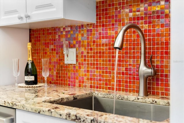 kitchen featuring tasteful backsplash, white cabinets, and sink