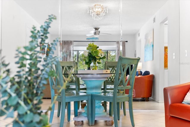 tiled dining space featuring ceiling fan with notable chandelier and a textured ceiling