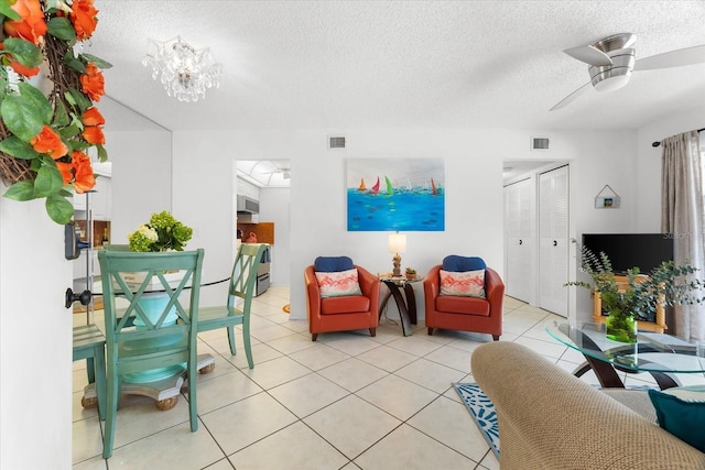 tiled living room with ceiling fan with notable chandelier and a textured ceiling