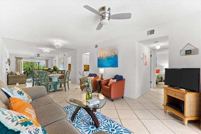 living room with a textured ceiling, ceiling fan, and light tile floors