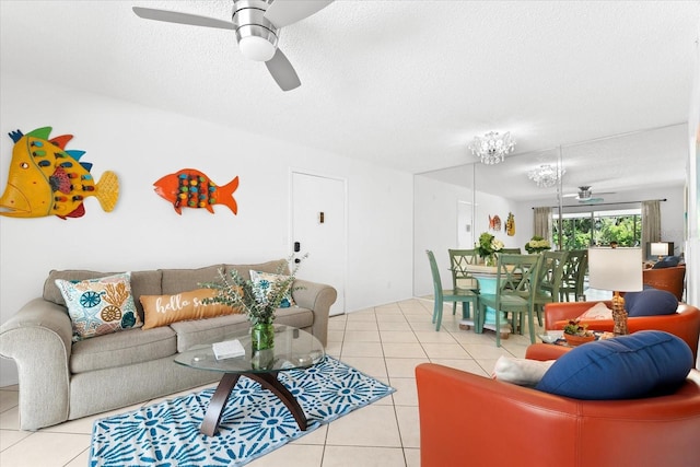 living room with ceiling fan, light tile floors, and a textured ceiling