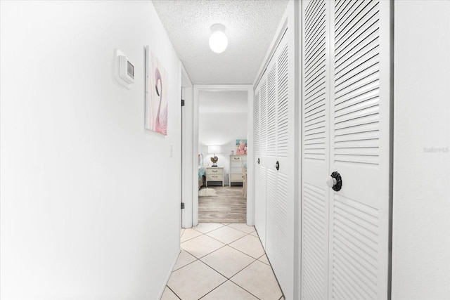 hallway featuring a textured ceiling and light tile floors