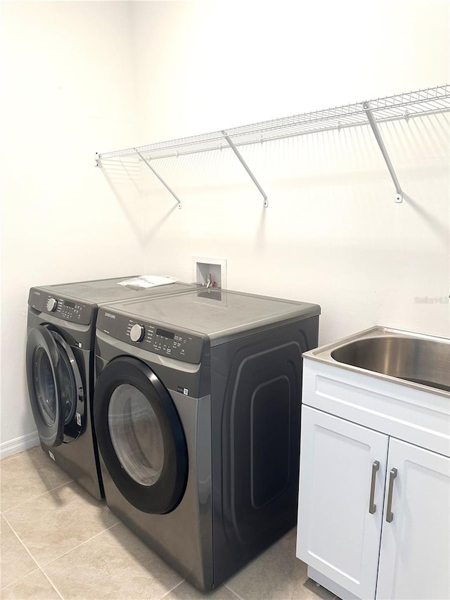 clothes washing area with cabinets, washer hookup, separate washer and dryer, and light tile floors