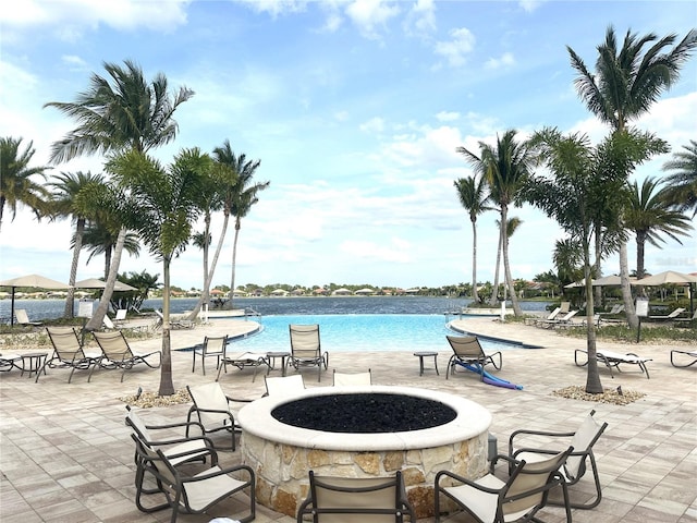 view of pool with a water view, a fire pit, and a patio