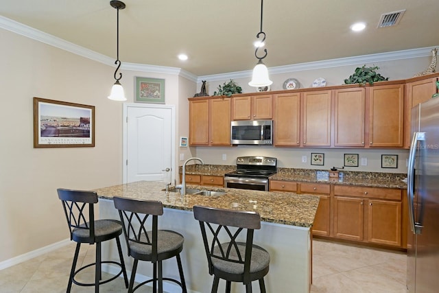 kitchen featuring decorative light fixtures, sink, appliances with stainless steel finishes, and a kitchen island with sink