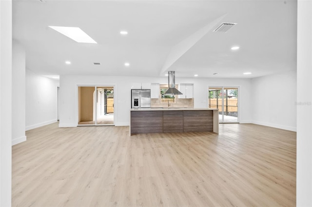 unfurnished living room with light hardwood / wood-style floors, sink, and a skylight