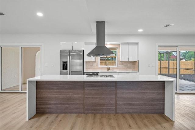 kitchen with white cabinetry, stainless steel refrigerator with ice dispenser, decorative backsplash, light wood-type flooring, and island exhaust hood