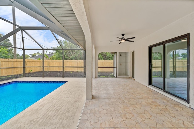 view of swimming pool with a patio, glass enclosure, and ceiling fan