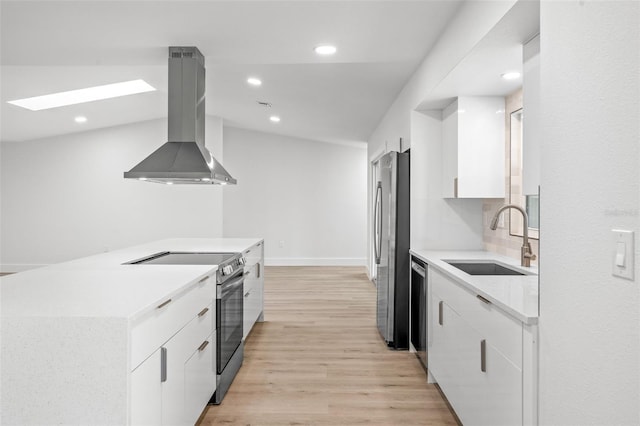 kitchen with lofted ceiling with skylight, light hardwood / wood-style flooring, appliances with stainless steel finishes, island range hood, and sink