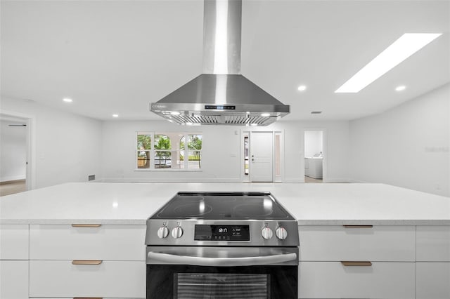 kitchen featuring range hood, stainless steel electric range, washer / clothes dryer, and white cabinets