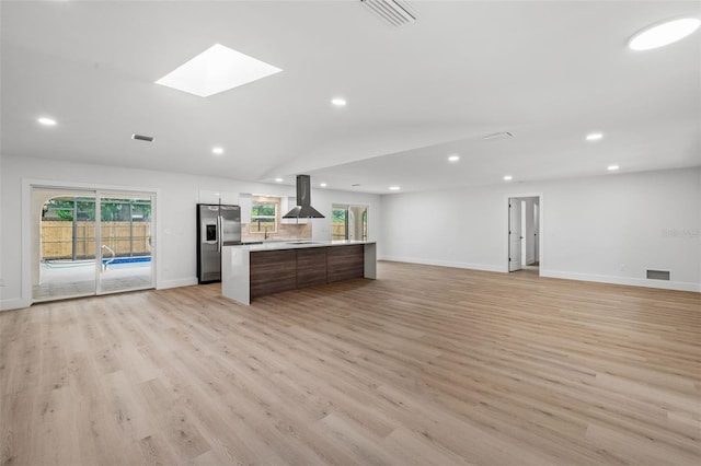 unfurnished living room with a skylight and light wood-type flooring