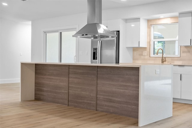 kitchen with light wood-type flooring, white cabinets, and island range hood