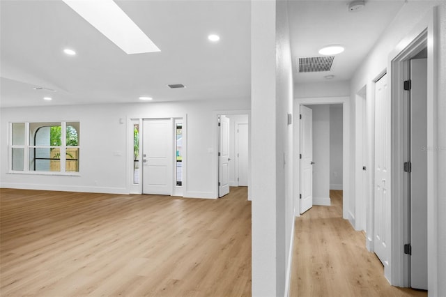 foyer entrance with a skylight and light hardwood / wood-style floors