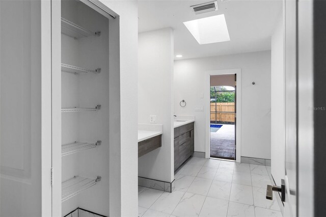 bathroom with a skylight, tile patterned floors, and vanity