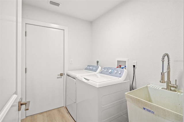 washroom featuring sink, light wood-type flooring, and independent washer and dryer