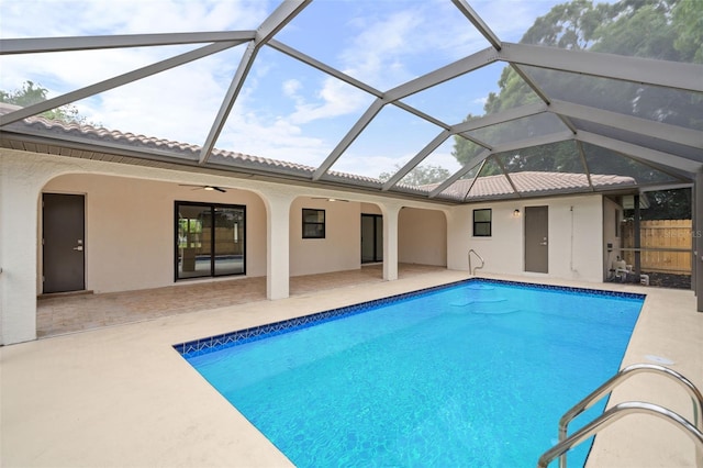 view of pool with a patio area, ceiling fan, and glass enclosure