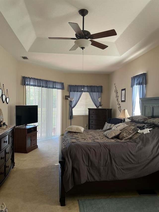 bedroom featuring access to outside, light colored carpet, ceiling fan, and a tray ceiling