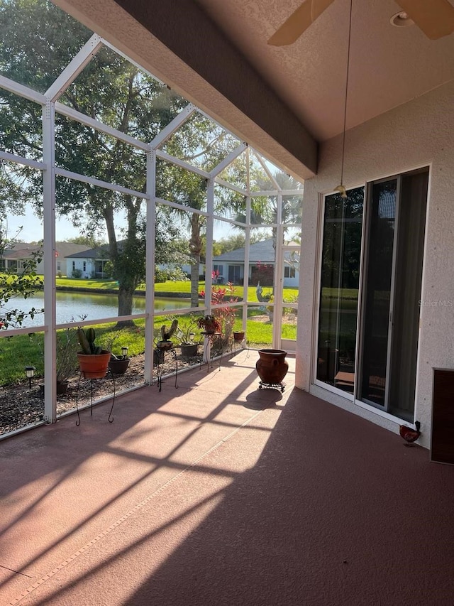 unfurnished sunroom with ceiling fan and a water view