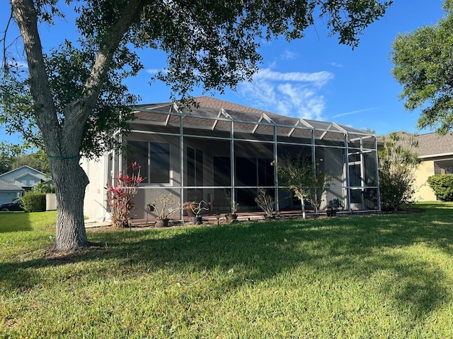 back of house with a yard and a lanai