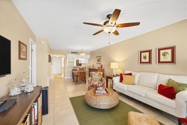 living room featuring ceiling fan, a textured ceiling, and light tile flooring