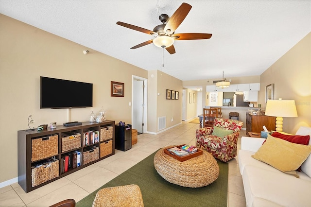 living room with a textured ceiling, ceiling fan, and light tile floors